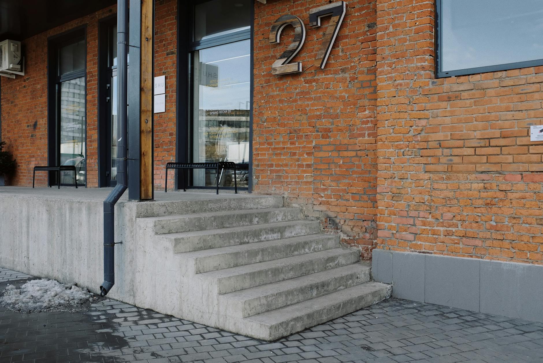 Betonowe schody z kostki przy ceglanej elewacji budynku nr 27