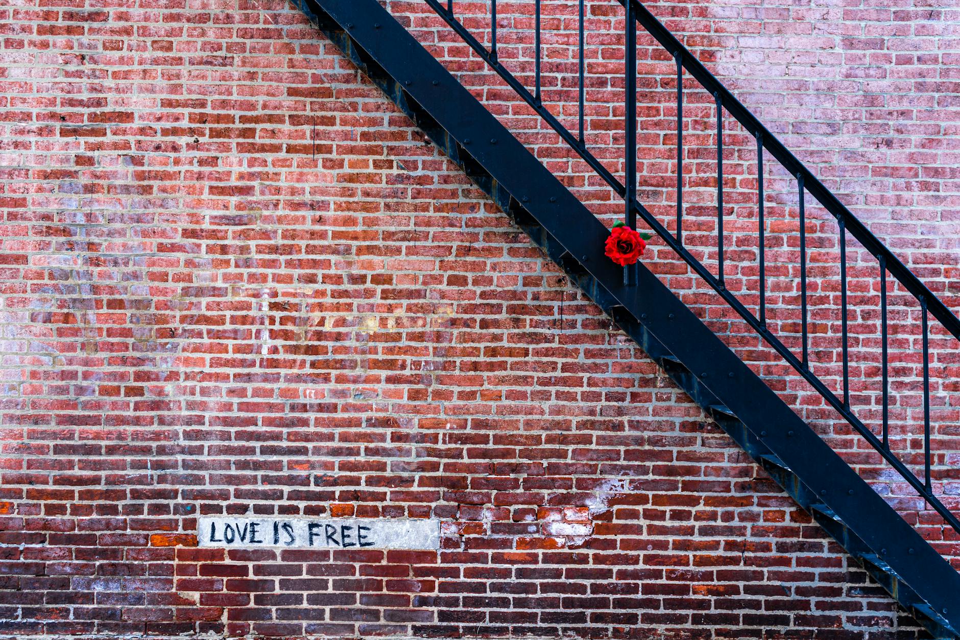 Ceglana ściana z metalowymi schodami i graffiti Love is free