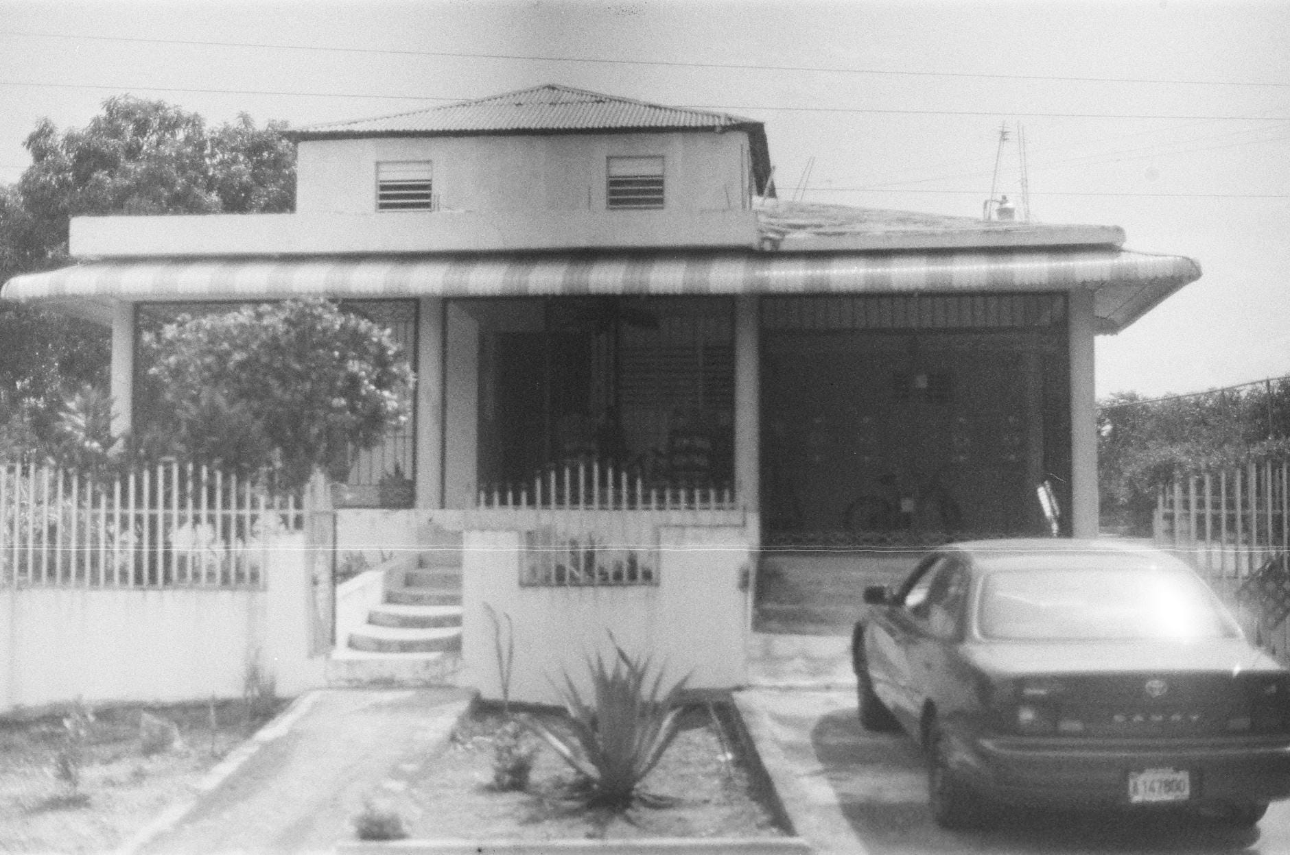 Czarno-białe zdjęcie domu jednorodzinnego z zaparkowanym autem na podjeździe