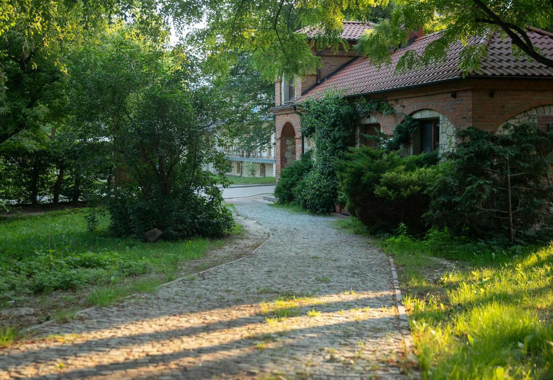 Kamienista ścieżka prowadząca przez ogród do ceglanego domu