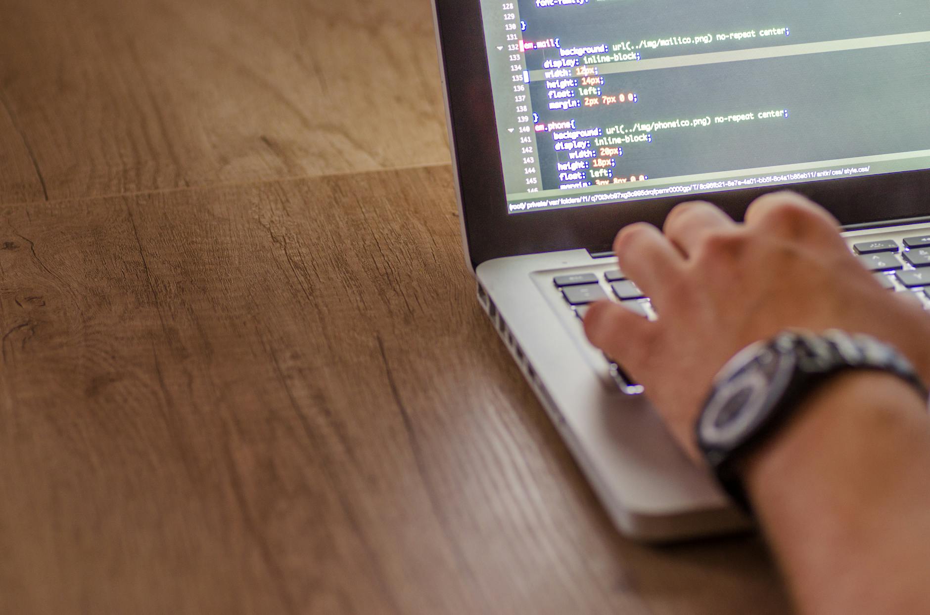 Osoba programująca na laptopie, widok z bliska na ekran z kodem