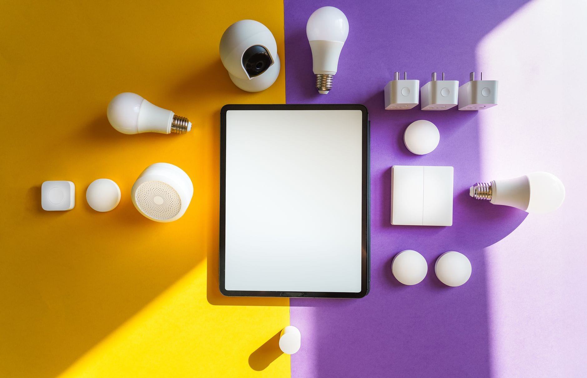 Tablet i urządzenia smart home na żółto‑fioletowym tle z góry